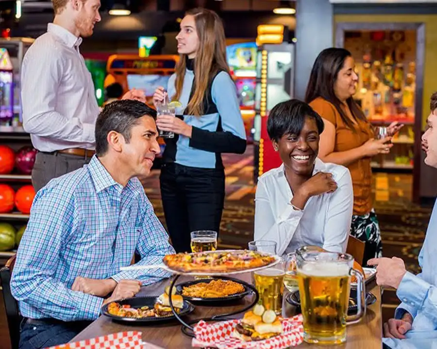 Coworkers enjoying food and drinks during a night out at Pro Bowl West in Fort Wayne, IN as part of a team-building event